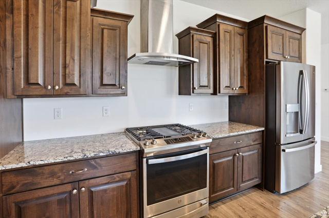 3636 West 910 South Syracuse, UT 84075 - Photo 34 of 70 Kitchen featuring rich wood cabinetry, light-toned countertops, stainless steel appliances, a gas range, and wood-finish flooring