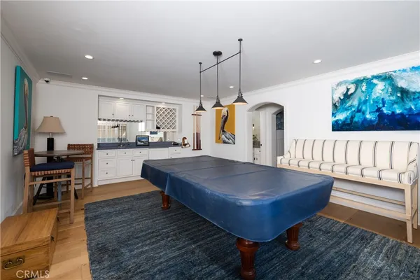 a room with wooden floor pool table and chairs