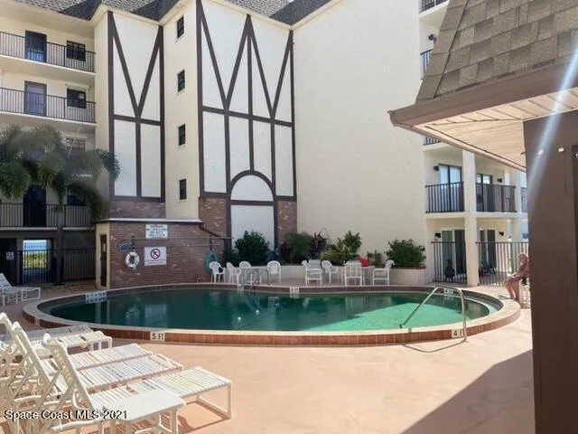 a front view of a multi story residential apartment building with yard and green space