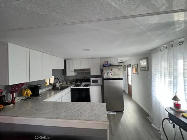 a kitchen with stainless steel appliances granite countertop a refrigerator sink stove microwave and cabinets