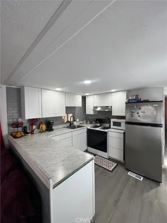 a kitchen with stainless steel appliances kitchen island granite countertop a stove refrigerator and a sink