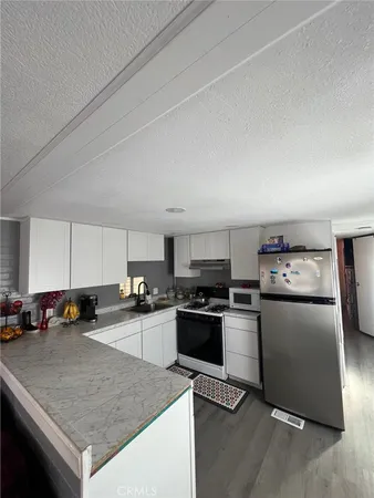 a kitchen with granite countertop stainless steel appliances a sink a stove top oven a counter space and cabinets