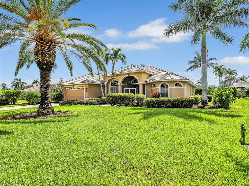 a view of a house with a big yard and palm trees
