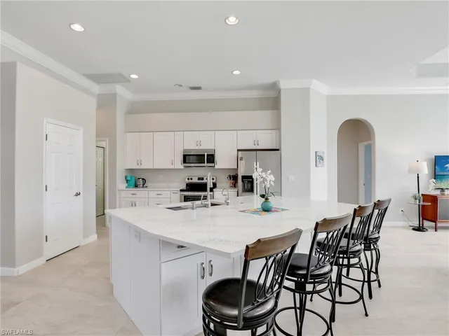 a kitchen with stainless steel appliances a dining table chairs and white cabinets