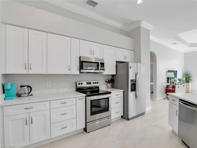 a living room with furniture a lamp and kitchen view