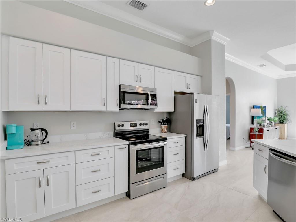 8845 Lely Island Circle Naples, FL 34113 - Photo 18 of 45 a kitchen with white cabinets and stainless steel appliances