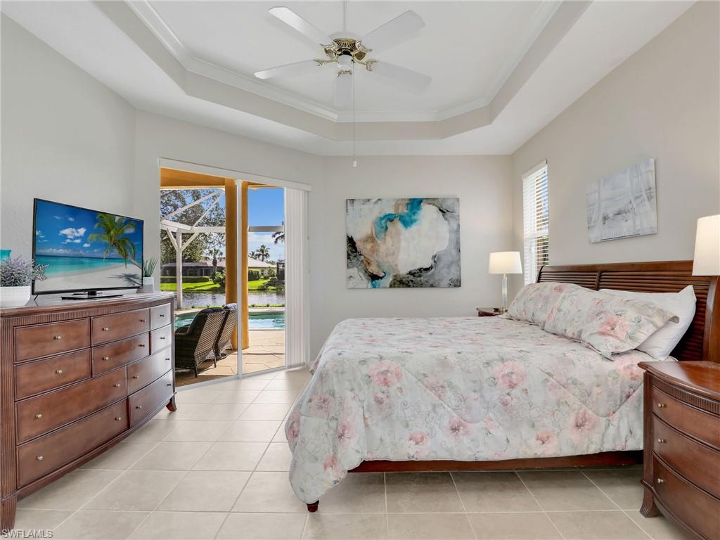 8845 Lely Island Circle Naples, FL 34113 - Photo 26 of 45 a bedroom with a large bed and a chandelier