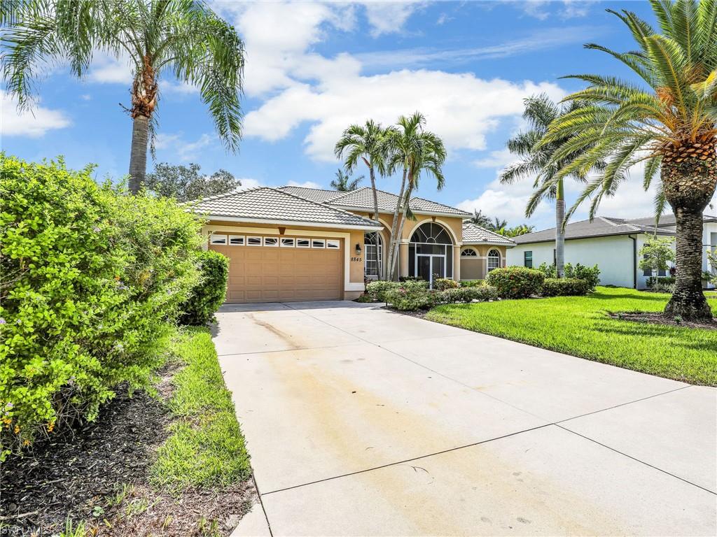 8845 Lely Island Circle Naples, FL 34113 - Photo 3 of 45 a front view of a house with a garden and trees