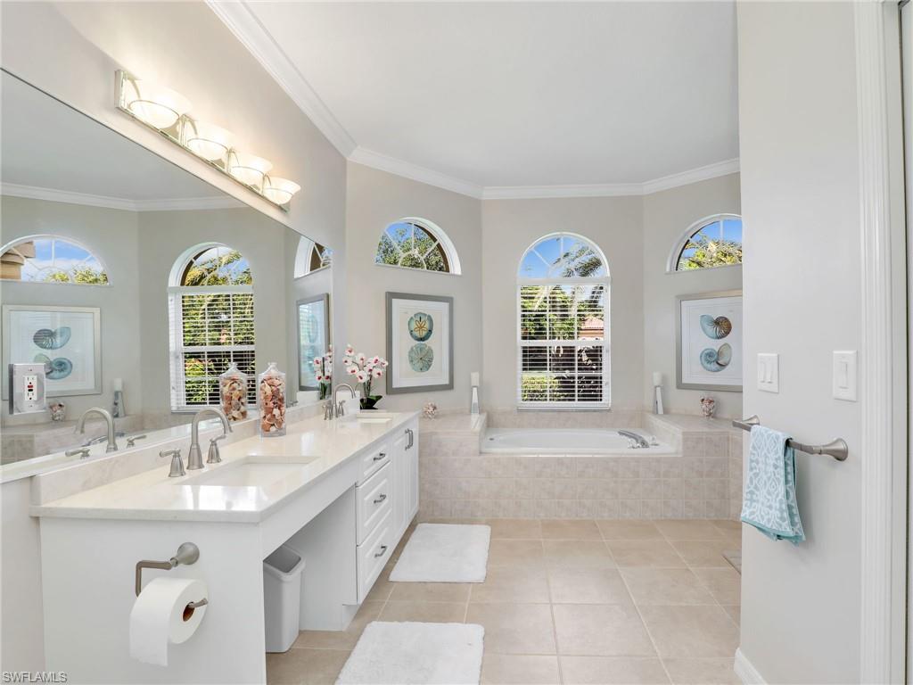 8845 Lely Island Circle Naples, FL 34113 - Photo 32 of 45 a spacious bathroom with a tub double vanity sinks and a large mirror