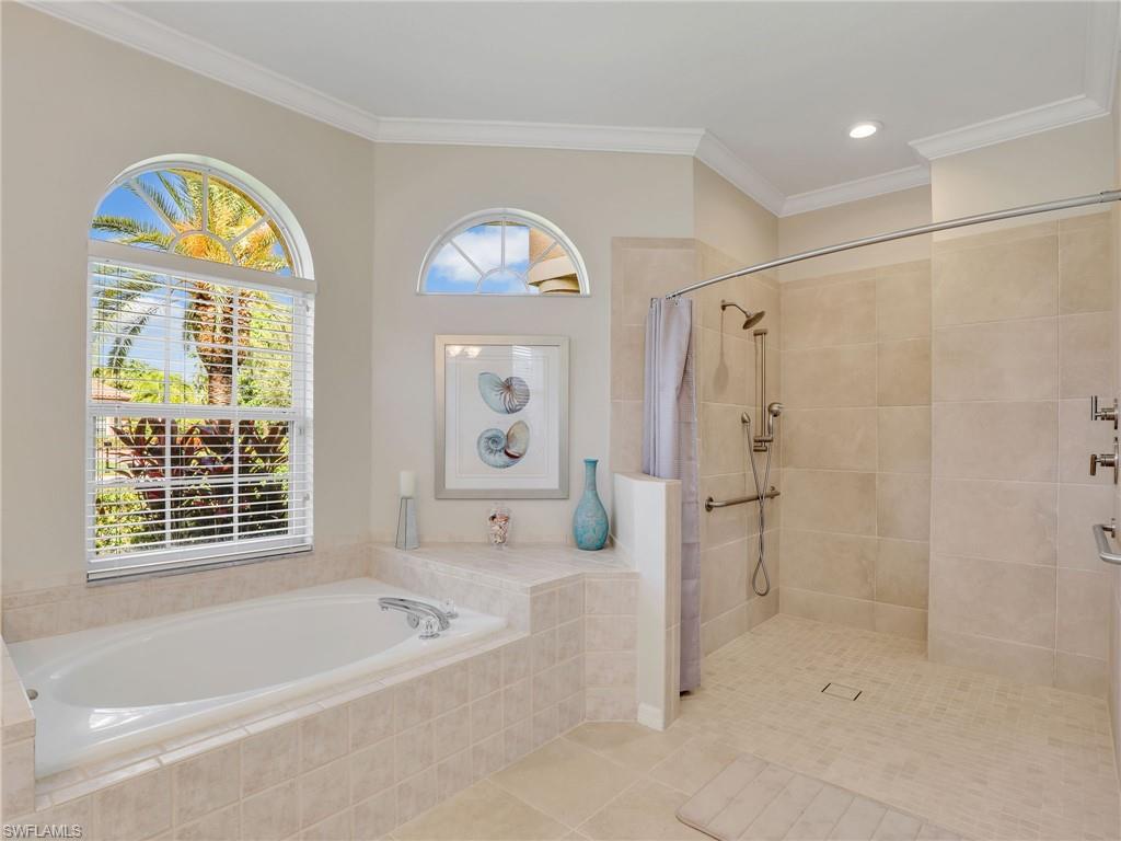 8845 Lely Island Circle Naples, FL 34113 - Photo 33 of 45 a bathroom with a tub a sink and a large mirror