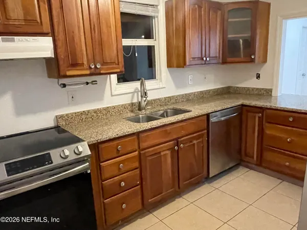 a kitchen with granite countertop a sink dishwasher stove and cabinets with wooden floor