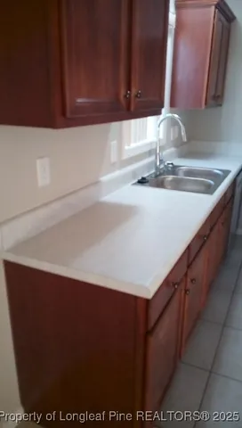 a kitchen with a sink and a dishwasher with wooden cabinet