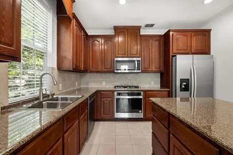a kitchen with stainless steel appliances granite countertop a sink stove microwave refrigerator and cabinets