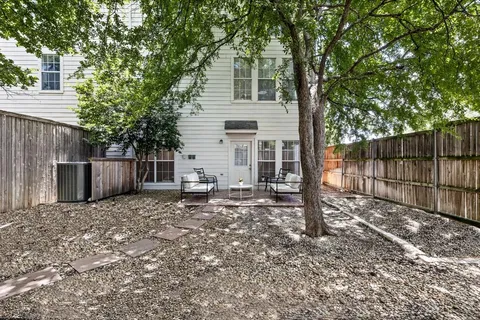 a view of a white house with a small yard and large tree