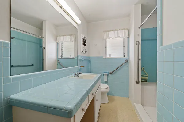 a bathroom with a granite countertop sink a toilet and shower