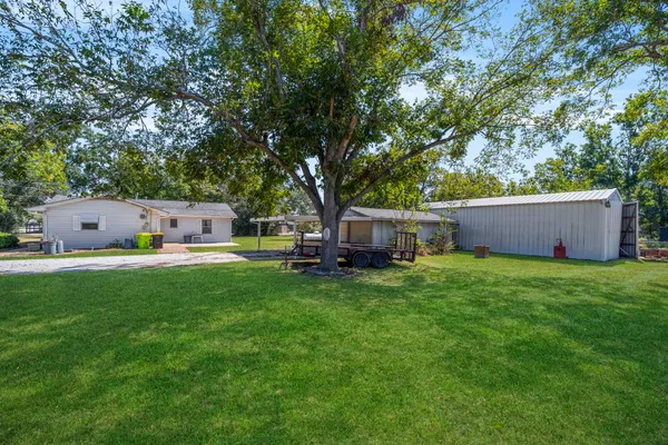a backyard of a house with table and chairs a barbeque and a large tree