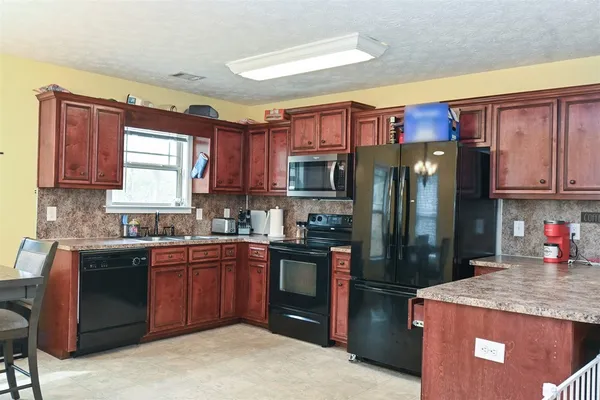 a kitchen with stainless steel appliances granite countertop a refrigerator a sink dishwasher a stove top oven a refrigerator and cabinets