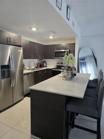 a kitchen with stainless steel appliances a table chairs refrigerator and microwave
