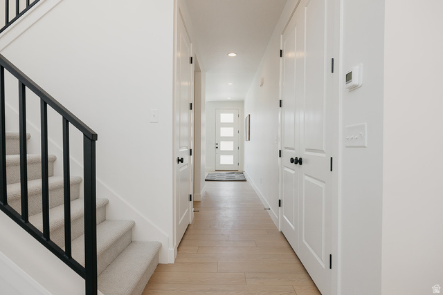5902 Canyon Rim Road, Unit 620 Lehi, UT 84048 - Photo 69 of 78 Foyer featuring light wood-finish flooring, a contemporary black metal baluster staircase, white paneled doors, black hardware, and recessed ceiling lighting