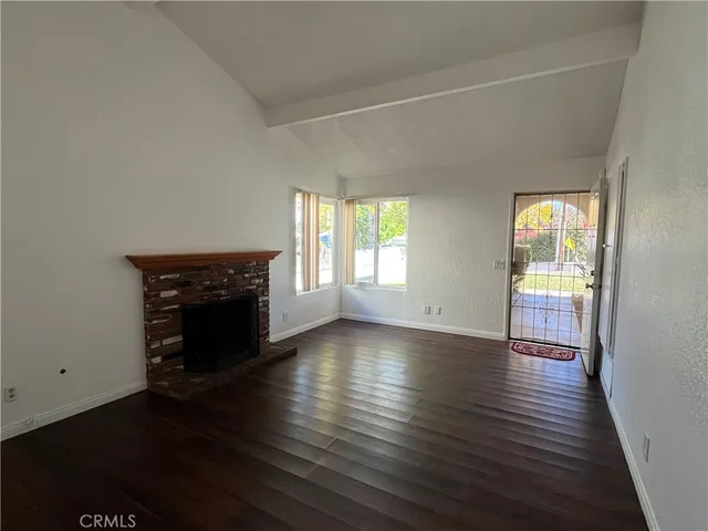 an empty room with wooden floor fireplace and windows