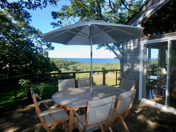 a patio with wooden floor a yard a table and chairs