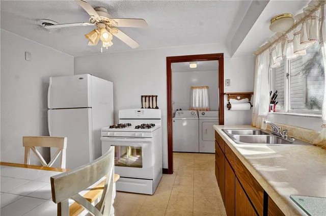 a kitchen with a refrigerator a stove top oven a sink dishwasher and a dining table with wooden floor