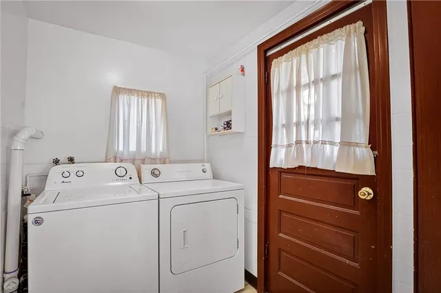 a view of washer and dryer with bathroom in the background