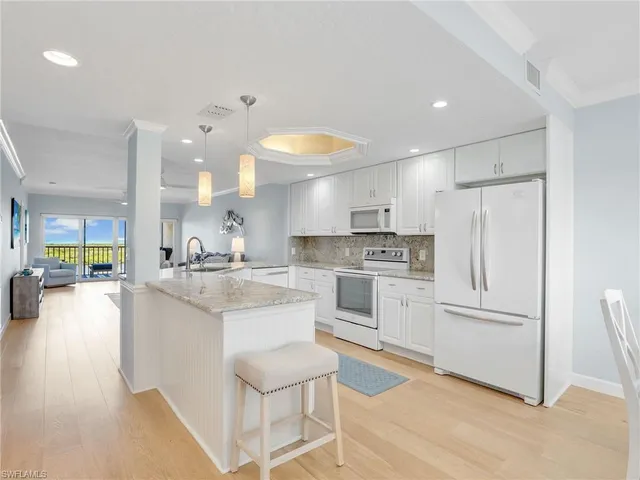 a large white kitchen with a large window and stainless steel appliances