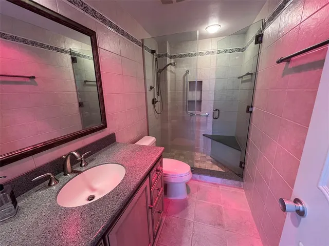 a bathroom with a granite countertop sink toilet a mirror and shower