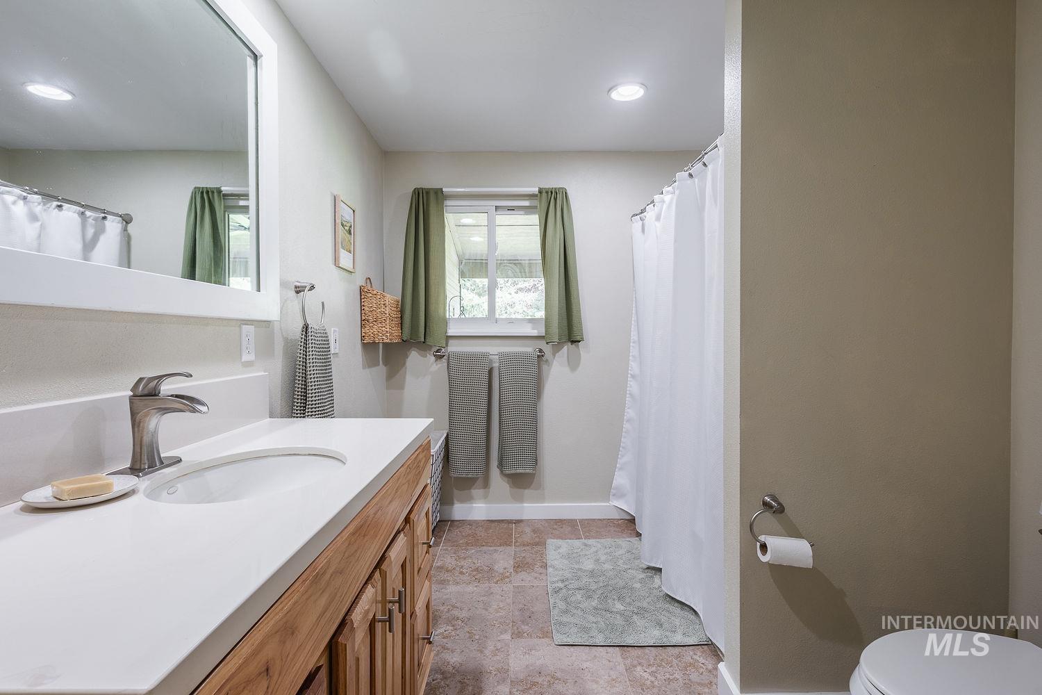 7166 South Cloverdale Road Boise, ID 83709 - Photo 18 of 50 Vanity with an integrated sink, polished chrome faucet, wood-finish cabinetry, and a framed mirror