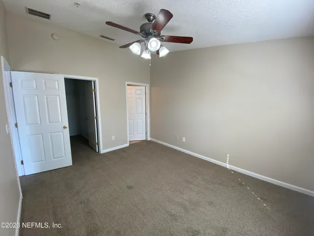an empty room with a chandelier fan and a window