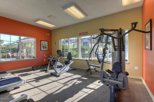 a room with gym equipment and large windows
