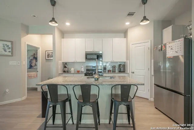 a kitchen with refrigerator a sink and chairs