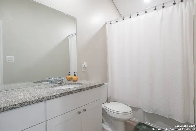 a bathroom with a granite countertop sink toilet and a mirror