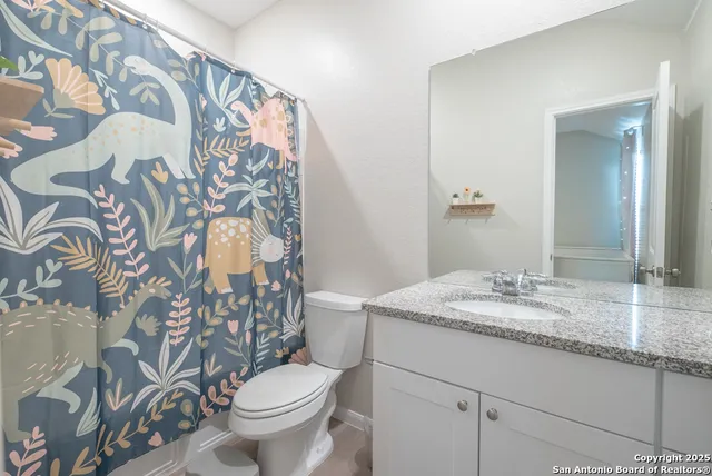 a bathroom with a granite countertop toilet sink and mirror