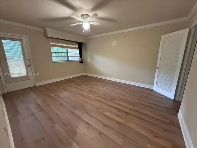 a view of empty room with wooden floor and fan