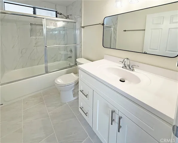 a bathroom with a granite countertop sink a toilet and shower