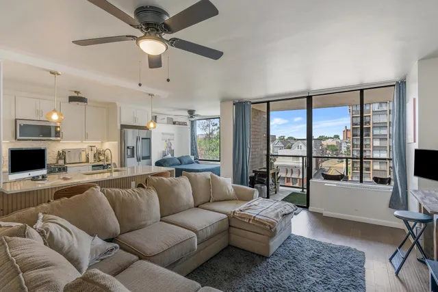 a living room with furniture and a large window with kitchen view