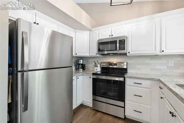 a white refrigerator freezer and a stove sitting inside of a kitchen with granite countertop stainless steel appliances