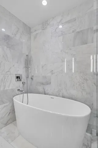 a white bath tub sitting next to a shower