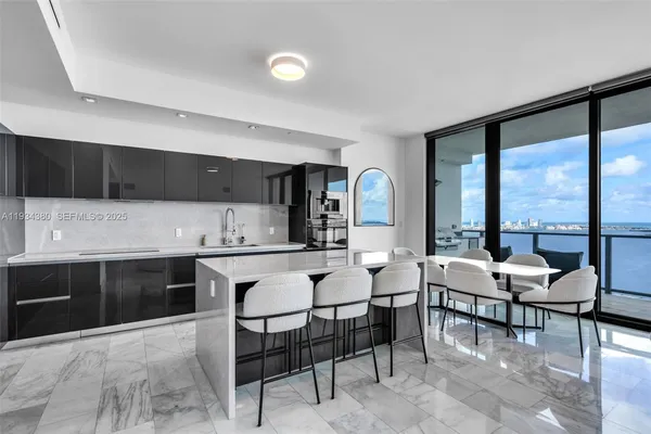 a open kitchen with stainless steel appliances kitchen island granite countertop a table and chairs in it