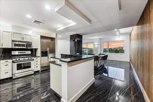 a kitchen with stainless steel appliances kitchen island granite countertop a stove and a refrigerator