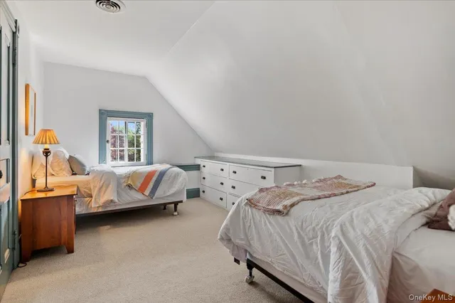 a bed sitting in a bedroom next to a window and a couch