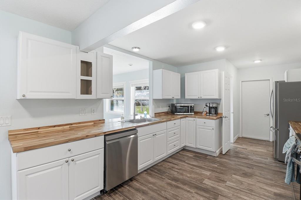 3619 North Suwanee Point Crystal River, FL 34428 - Photo 12 of 54 a kitchen with a sink stainless steel appliances white cabinets and wooden floor