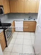 a kitchen with granite countertop a stove a sink and a white cabinets