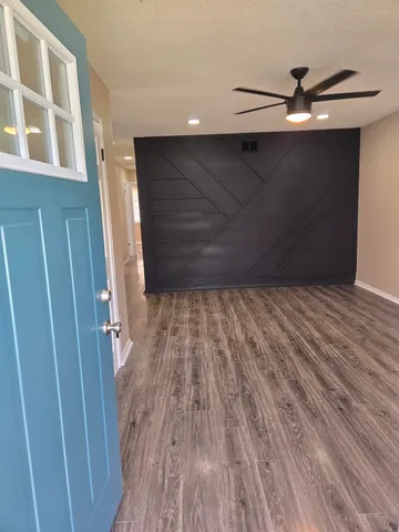 a view of a room with wooden floor and a ceiling fan