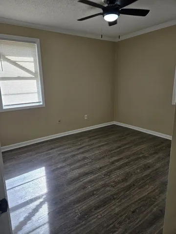 an empty room with wooden floor fan and windows