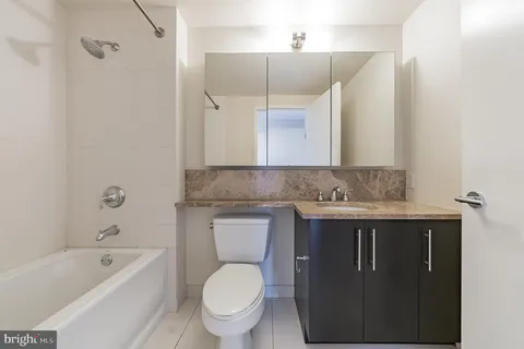 a bathroom with a granite countertop toilet sink and mirror