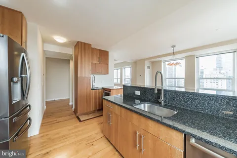 a kitchen with granite countertop a sink a counter top space cabinets stainless steel appliances and a window