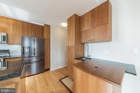 a kitchen with stainless steel appliances granite countertop a refrigerator a sink and a stove